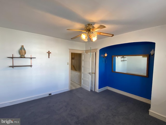 spare room featuring ceiling fan and dark carpet