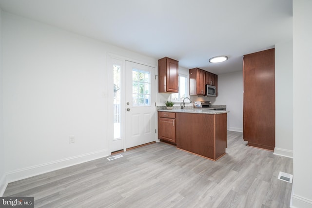 kitchen with stove, light hardwood / wood-style floors, and sink