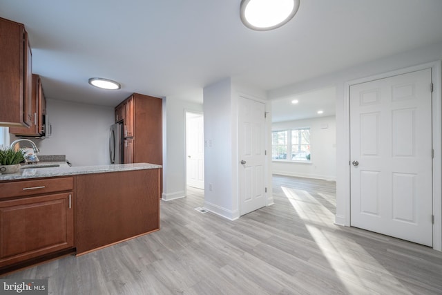 kitchen with stainless steel refrigerator, sink, and light hardwood / wood-style floors