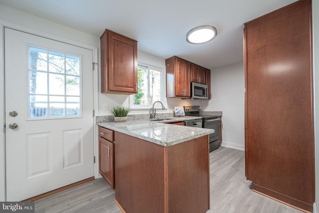 kitchen featuring light stone countertops, stainless steel appliances, sink, light hardwood / wood-style floors, and plenty of natural light