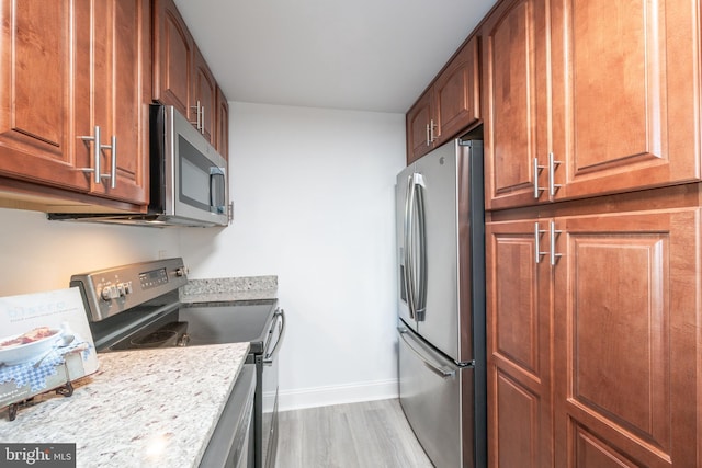 kitchen featuring light stone countertops, light hardwood / wood-style flooring, and appliances with stainless steel finishes