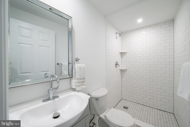 bathroom with a tile shower, sink, and toilet