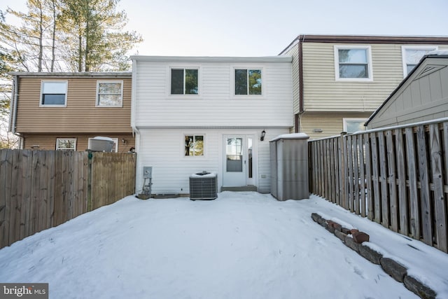 snow covered rear of property featuring cooling unit