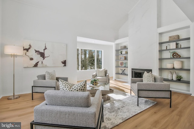 living room with built in features, a towering ceiling, and wood-type flooring