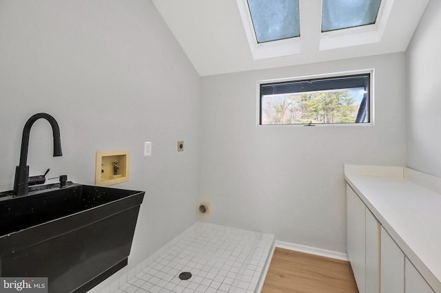 laundry room with electric dryer hookup, cabinets, sink, hookup for a washing machine, and light hardwood / wood-style floors