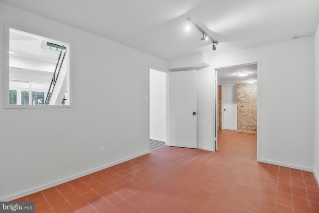 spare room with brick wall and track lighting