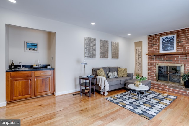 living room with wet bar, light hardwood / wood-style floors, and a fireplace