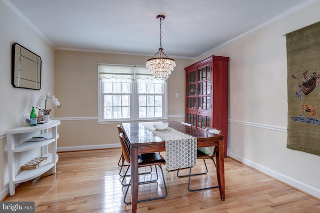 dining room with ornamental molding, a chandelier, and light hardwood / wood-style flooring