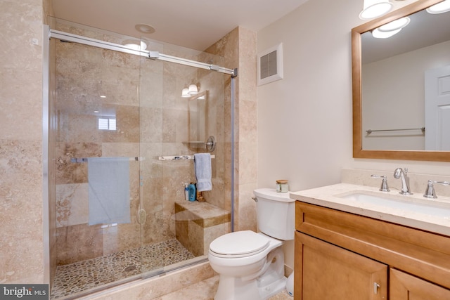 bathroom featuring vanity, toilet, and a shower with shower door