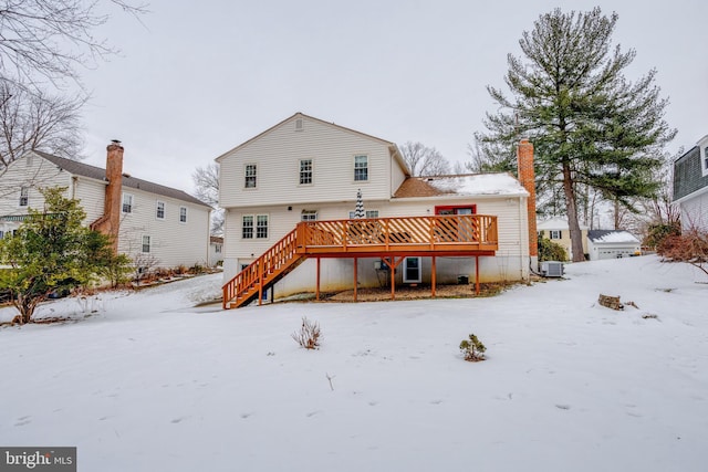 snow covered rear of property featuring central AC unit and a wooden deck