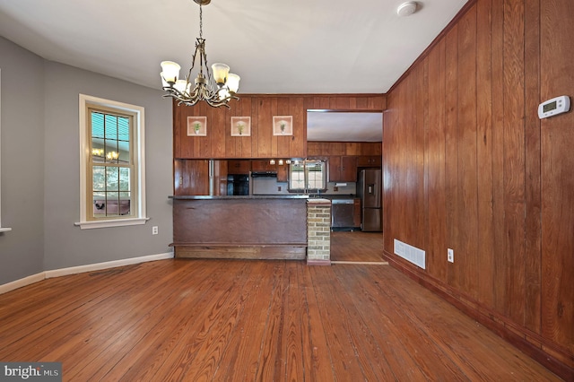 kitchen featuring hardwood / wood-style floors, a notable chandelier, stainless steel appliances, and hanging light fixtures