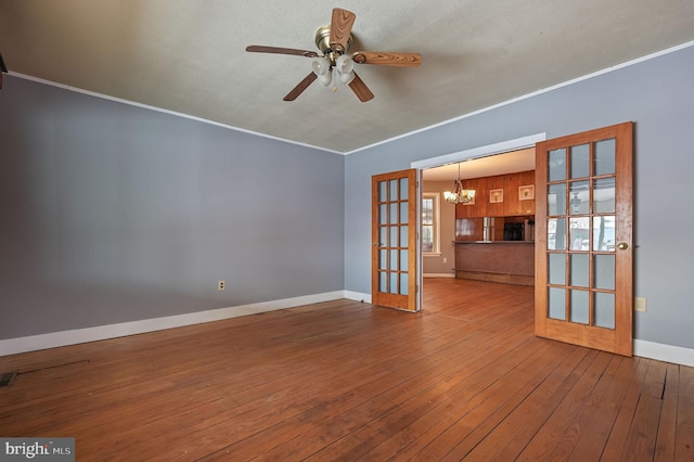 spare room with hardwood / wood-style flooring, ceiling fan with notable chandelier, ornamental molding, and french doors