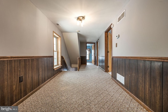 hall featuring carpet floors and wood walls