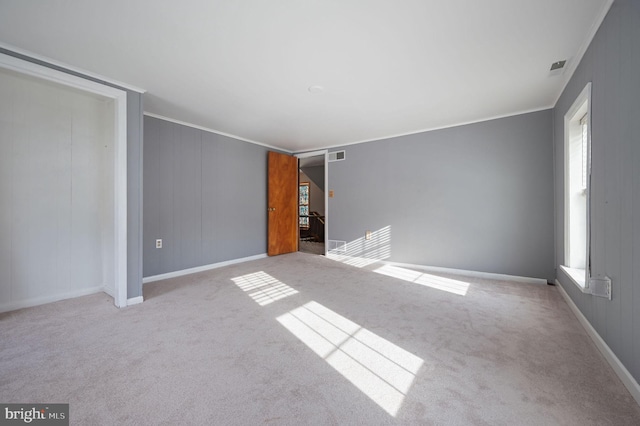 empty room featuring light carpet, plenty of natural light, and crown molding