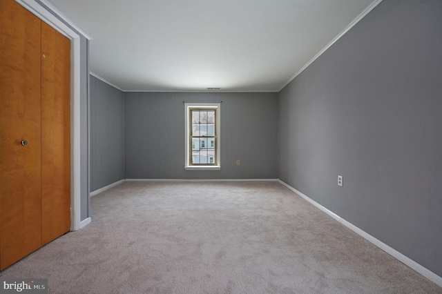 carpeted spare room featuring crown molding