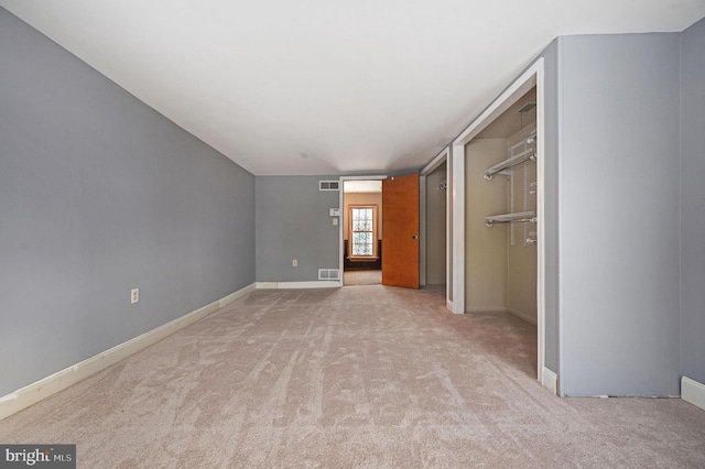 unfurnished bedroom with light colored carpet and a closet