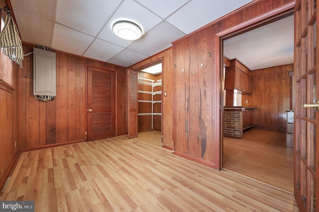 interior space featuring wooden walls, a drop ceiling, and light hardwood / wood-style floors