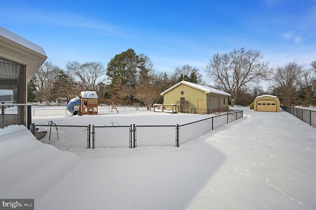 yard layered in snow with a garage and an outdoor structure