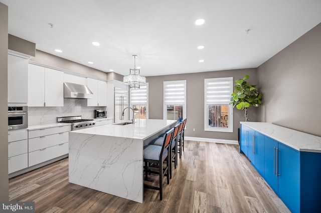 kitchen featuring white cabinets, oven, sink, and a spacious island