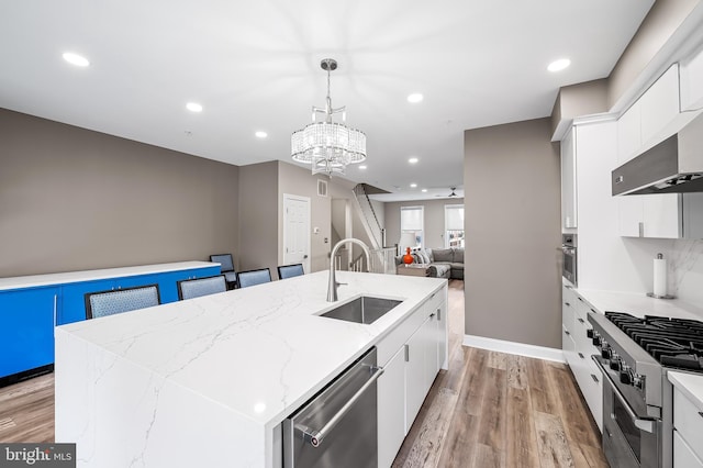 kitchen with sink, white cabinetry, appliances with stainless steel finishes, and a center island with sink