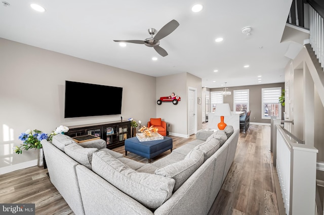 living room featuring ceiling fan with notable chandelier and hardwood / wood-style floors