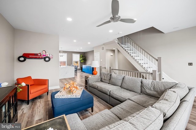 living room featuring ceiling fan with notable chandelier and hardwood / wood-style floors