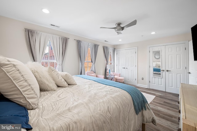 bedroom with ceiling fan, two closets, and wood-type flooring