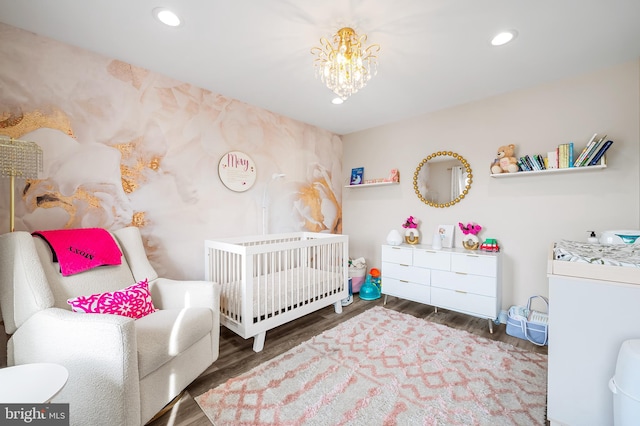 bedroom featuring a crib, washer / clothes dryer, an inviting chandelier, and dark wood-type flooring