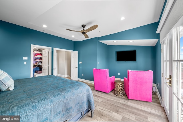 bedroom with a walk in closet, ceiling fan, light hardwood / wood-style flooring, and a closet