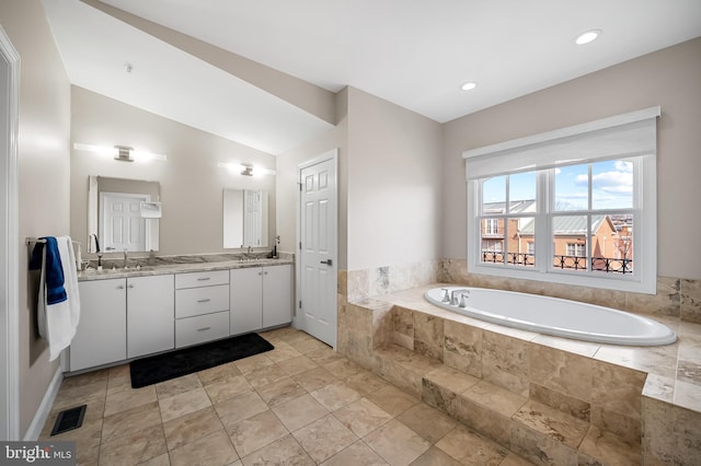 bathroom featuring tiled bath, lofted ceiling, and vanity