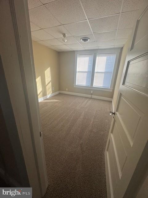 empty room featuring a paneled ceiling and carpet