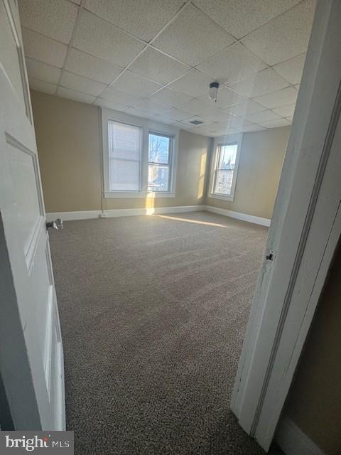 empty room featuring carpet floors and a paneled ceiling