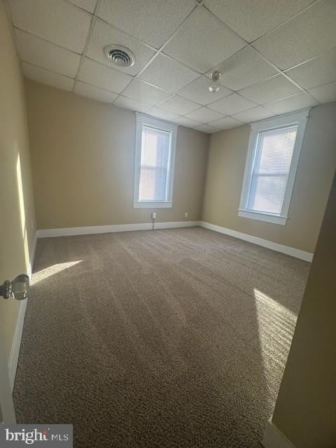 spare room featuring a paneled ceiling and carpet floors