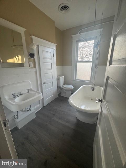 bathroom featuring a washtub, hardwood / wood-style flooring, toilet, and sink