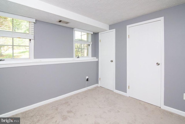 spare room with light colored carpet and a textured ceiling