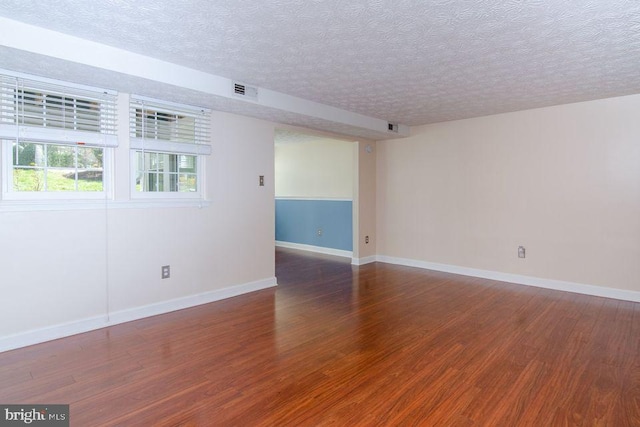 unfurnished room featuring a textured ceiling and dark hardwood / wood-style floors