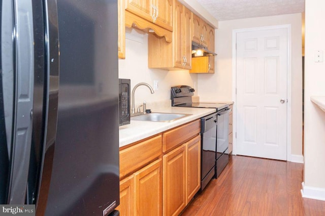 kitchen featuring black appliances, dark hardwood / wood-style flooring, sink, and a textured ceiling