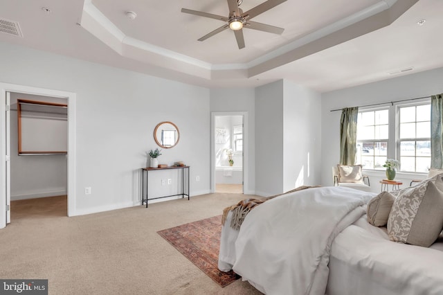 carpeted bedroom with ceiling fan, ensuite bathroom, and a raised ceiling