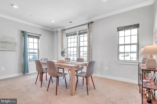 carpeted dining room with ornamental molding