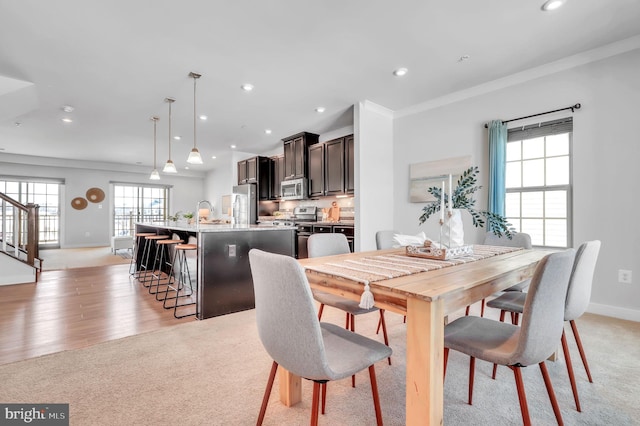 carpeted dining space featuring crown molding and sink