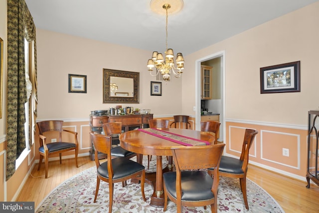 dining space featuring light wood-type flooring and an inviting chandelier