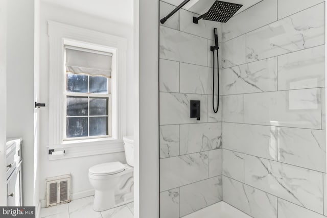 bathroom featuring a tile shower and toilet