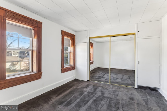 unfurnished bedroom featuring a closet and dark colored carpet