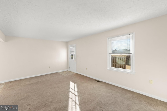 unfurnished room featuring a textured ceiling and light carpet