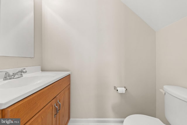 bathroom featuring vanity, toilet, and lofted ceiling