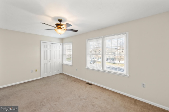 unfurnished bedroom featuring ceiling fan, a closet, and light colored carpet