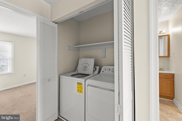 laundry area featuring light carpet, a textured ceiling, and separate washer and dryer