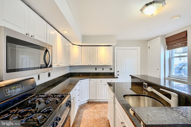 kitchen featuring white cabinetry, sink, dark stone countertops, black range with gas cooktop, and light tile patterned flooring