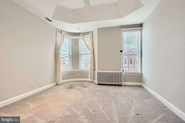 unfurnished room featuring light colored carpet, radiator, and a tray ceiling