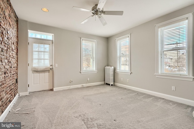 spare room featuring ceiling fan, radiator heating unit, and light carpet